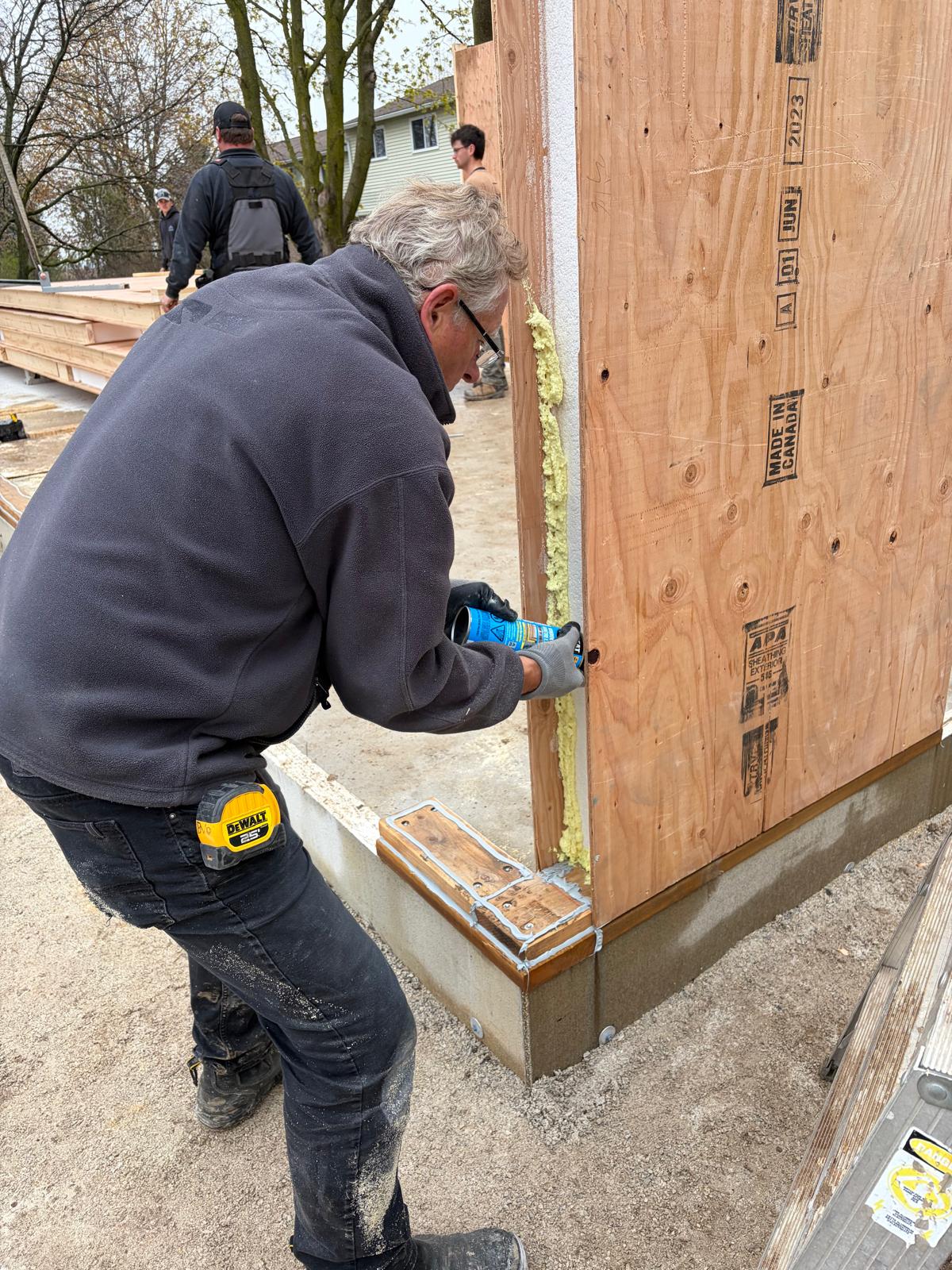 Close-up of worker applying expanding foam sealant to SIP panel joint for airtight connection